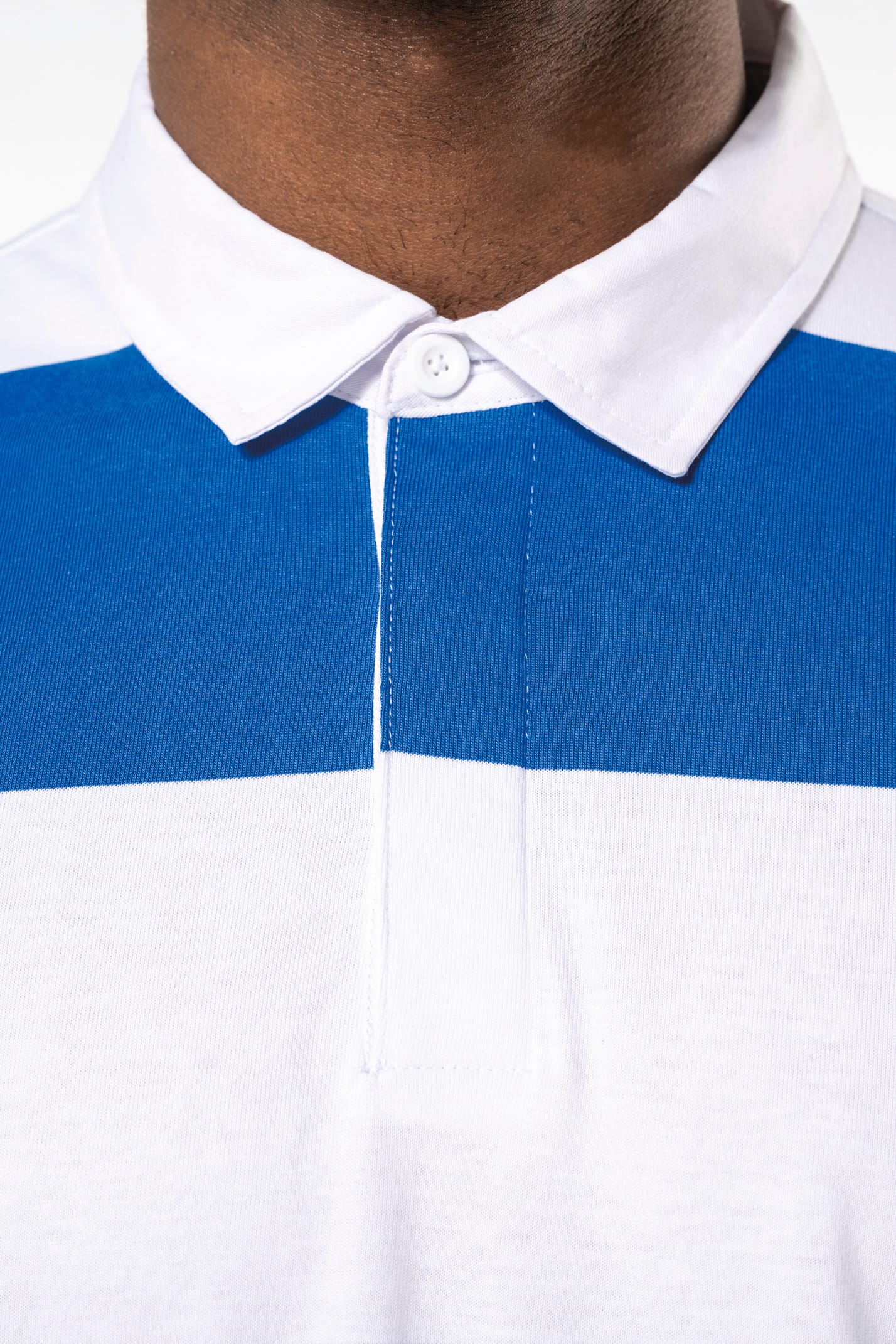 Homme brun qui porte un polo rugby rayé bleu et blanc. 