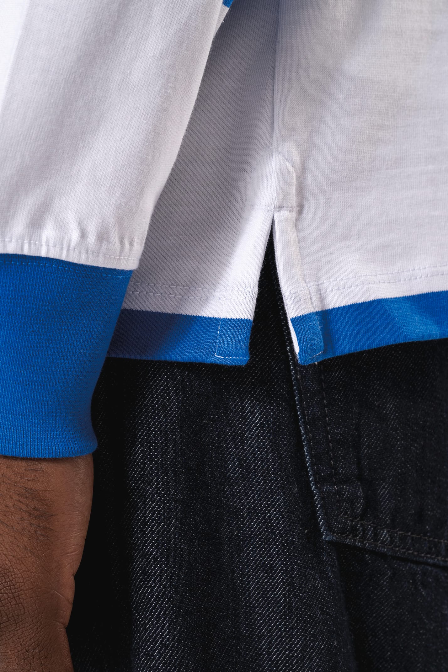 Homme brun qui porte un polo rugby rayé bleu et blanc. 