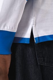 Homme brun qui porte un polo rugby rayé bleu et blanc. 