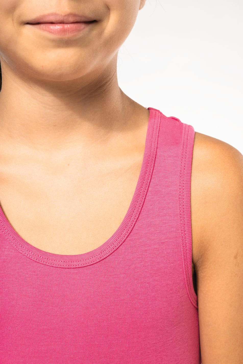 Fillette brune cheveux attachés qui porte un débardeur Fuchsia.