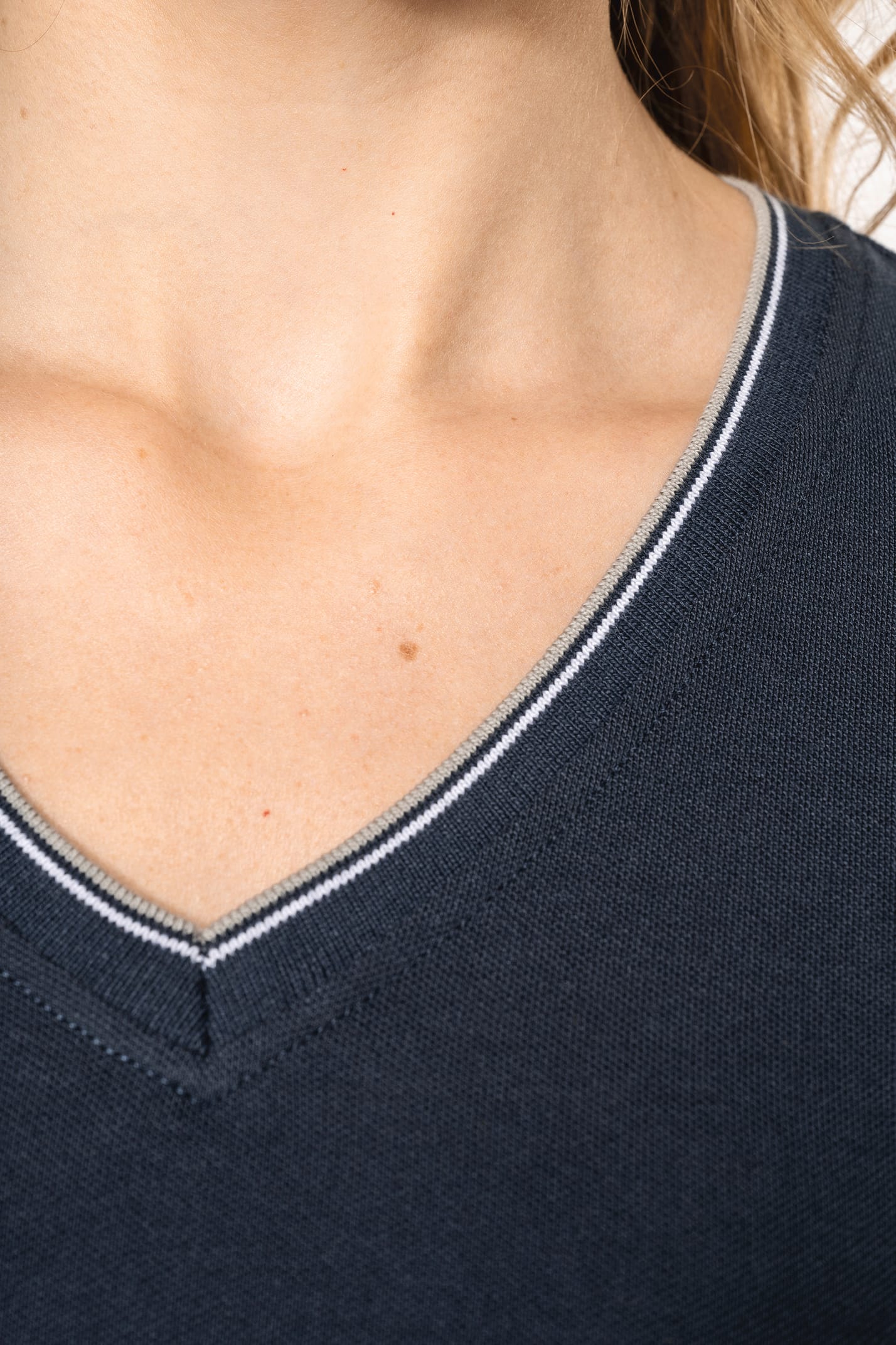 Femme blonde cheveux longs qui porte un T-shirt maille piquée col V Navy.