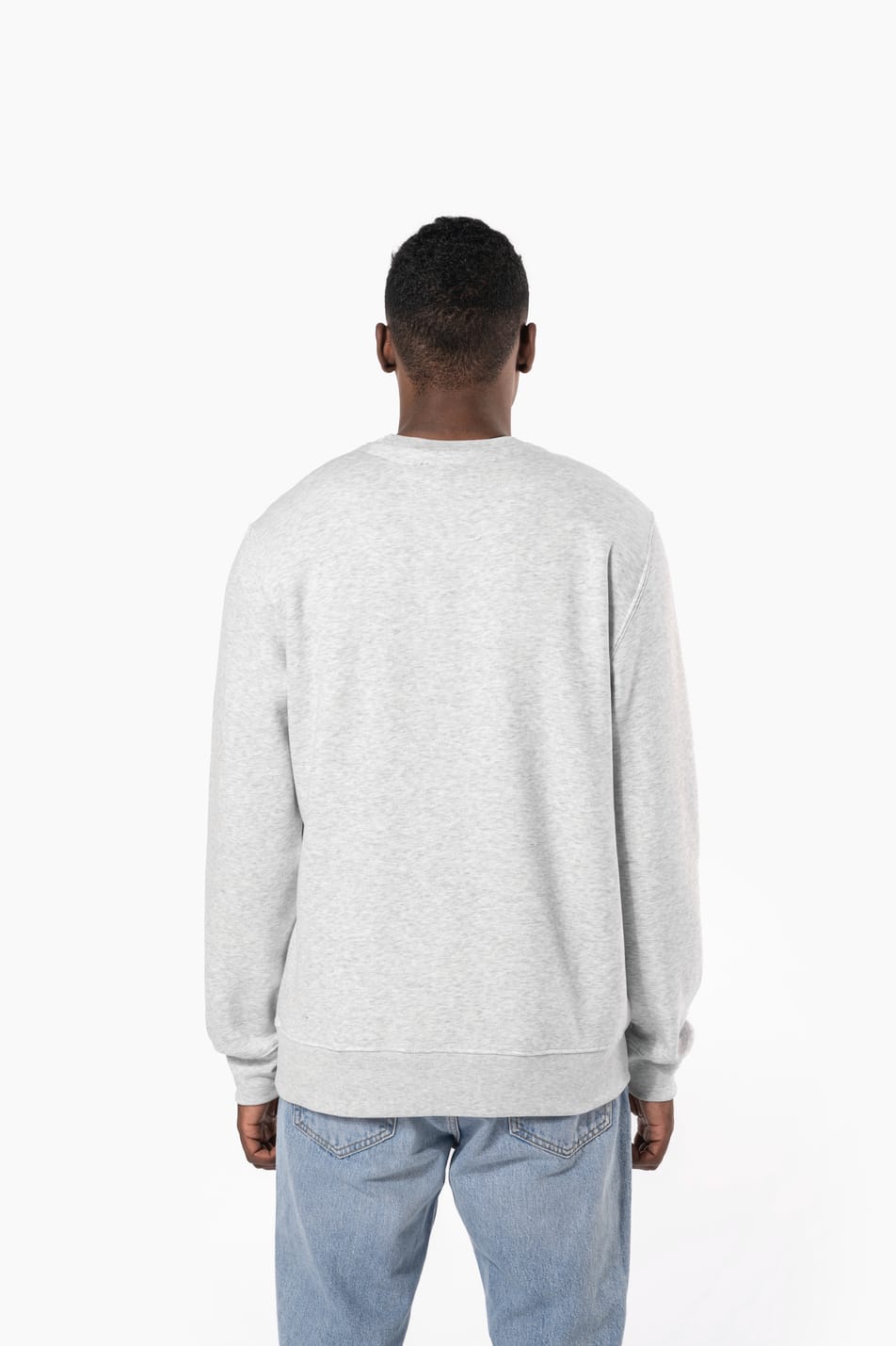 Homme brun cheveux courts qui porte un sweat clair chiné.