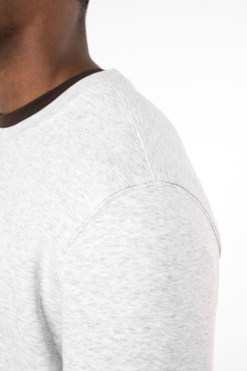 Homme brun cheveux courts qui porte un sweat clair chiné.