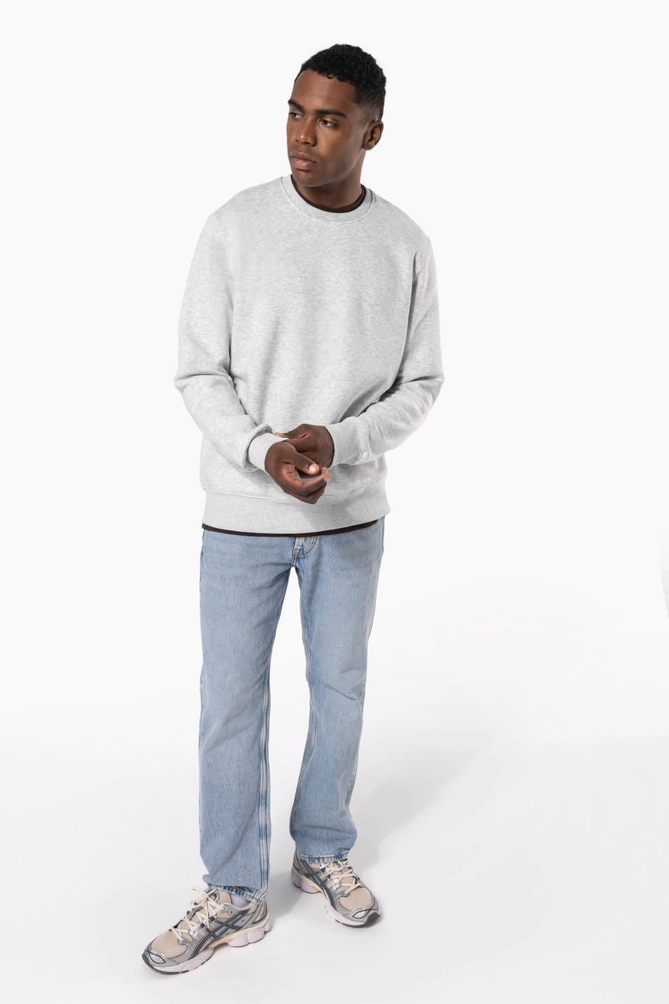 Homme brun cheveux courts qui porte un sweat clair chiné.