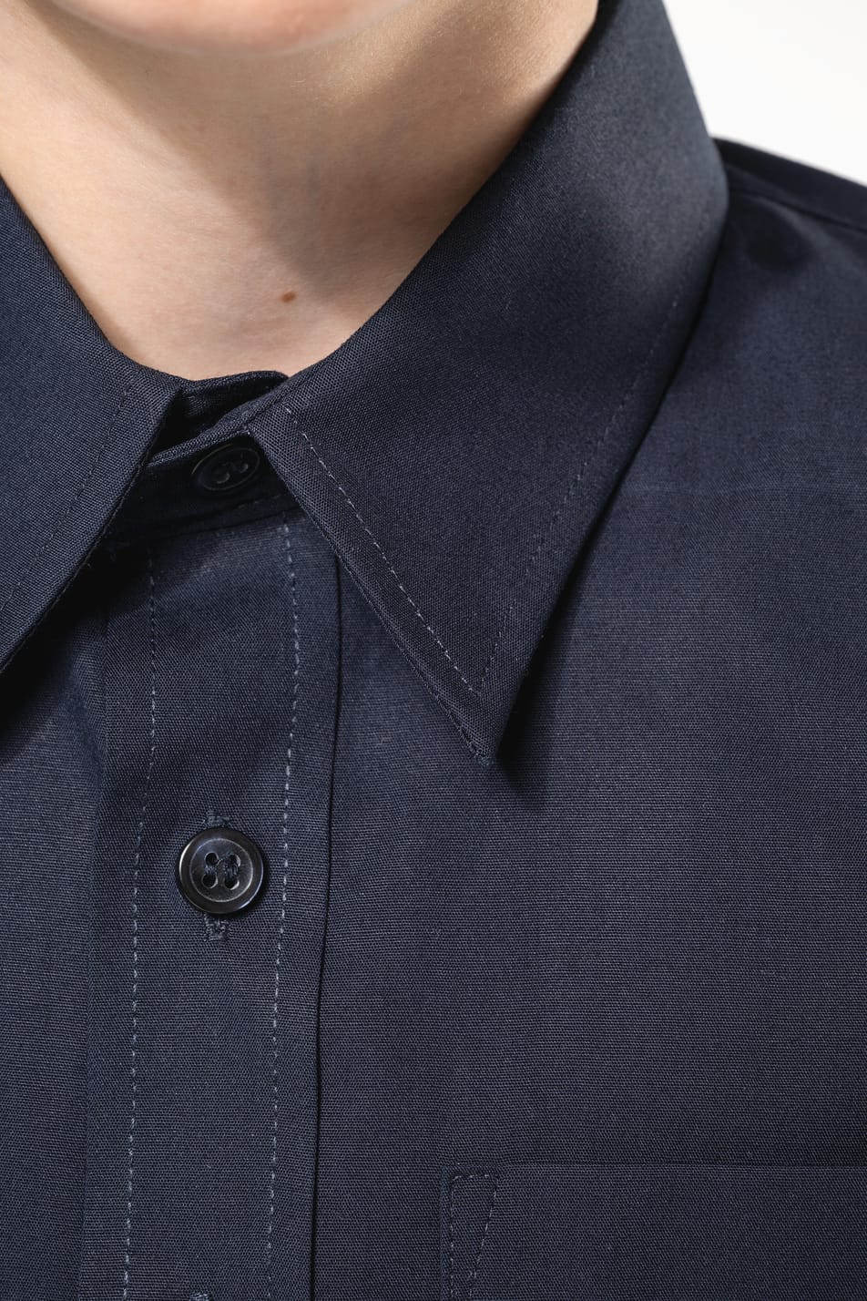 Jeune garçon cheveux courts châtain qui porte une chemise popeline manches courtes Navy.