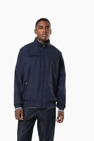 Homme brun cheveux courts qui porte un blouson style bomber américain bleu marine.