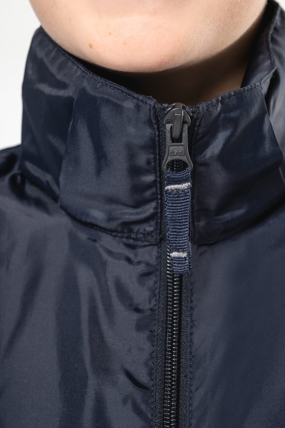 Jeune garçon cheveux courts châtain qui porte un coupe-vent non doublé Navy.