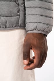 Homme brun avec un bonnet noir qui porte une doudoune légère à capuche argentée.