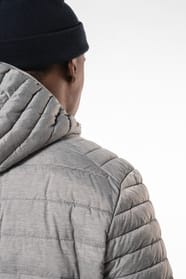 Homme brun avec un bonnet noir qui porte une doudoune légère à capuche argentée.