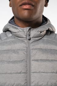 Homme brun avec un bonnet noir qui porte une doudoune légère à capuche argentée.