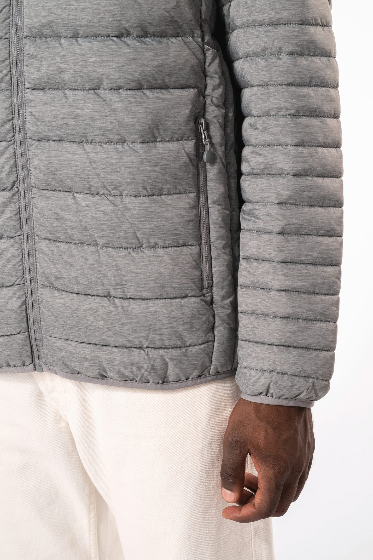 Homme brun avec un bonnet noir qui porte une doudoune légère à capuche argentée.