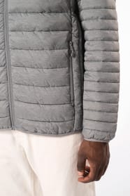 Homme brun avec un bonnet noir qui porte une doudoune légère à capuche argentée.