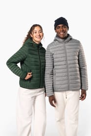 Femme aux cheveux frisls attachés et homme brun avec bonnet noir qui portent des doudounes légères à capuches vert forêt et argenté.