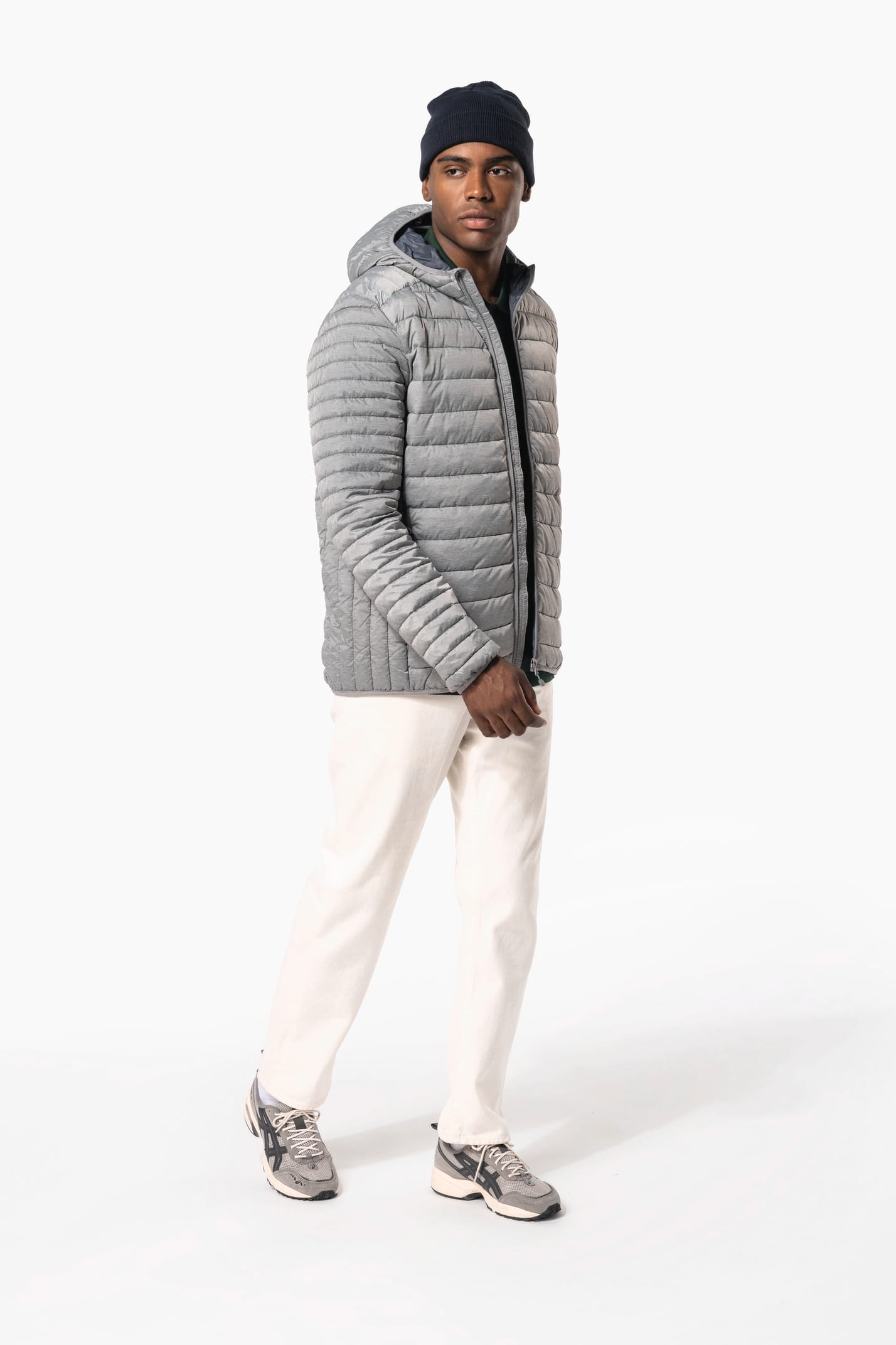 Homme brun avec un bonnet noir qui porte une doudoune légère à capuche argentée.