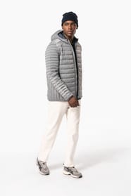 Homme brun avec un bonnet noir qui porte une doudoune légère à capuche argentée.