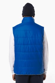 Jeune homme avec bonnet noir qui porte un bodywarmer matelassé bleu clair.