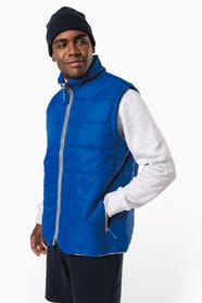 Jeune homme avec bonnet noir qui porte un bodywarmer matelassé bleu clair.