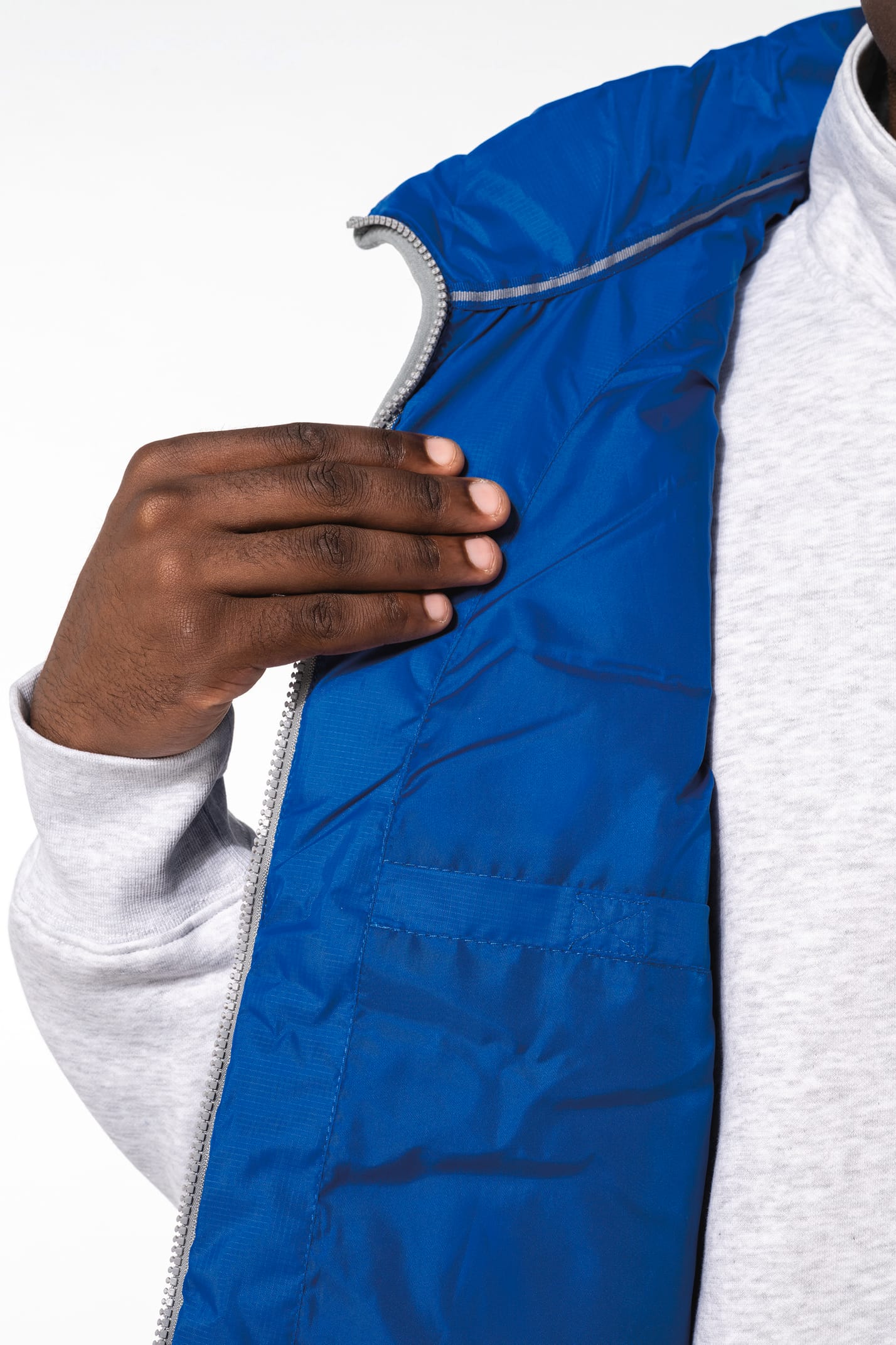 Jeune homme avec bonnet noir qui porte un bodywarmer matelassé bleu clair.