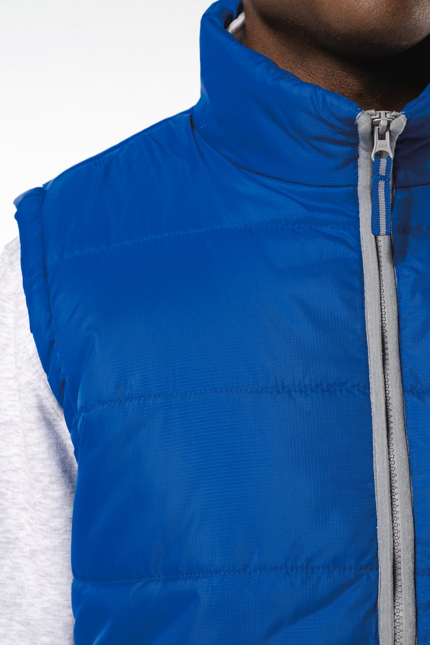 Jeune homme avec bonnet noir qui porte un bodywarmer matelassé bleu clair.