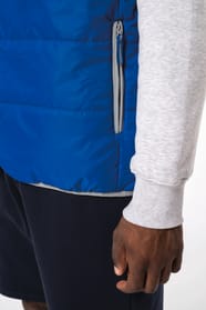 Jeune homme avec bonnet noir qui porte un bodywarmer matelassé bleu clair.