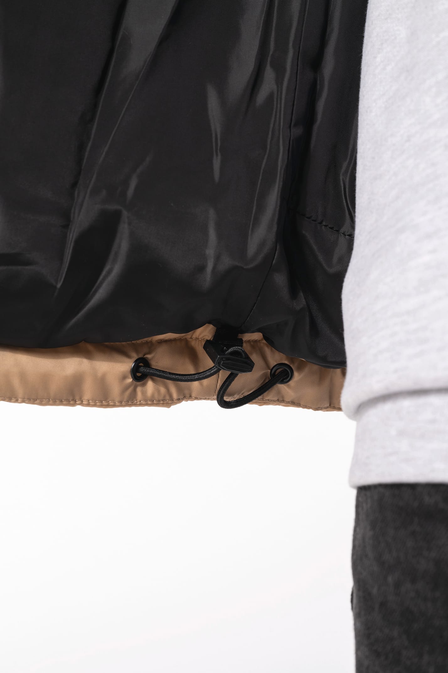 Jeune homme avec bonnet qui porte un bodywarmer matelassé bicolore beige et noir.