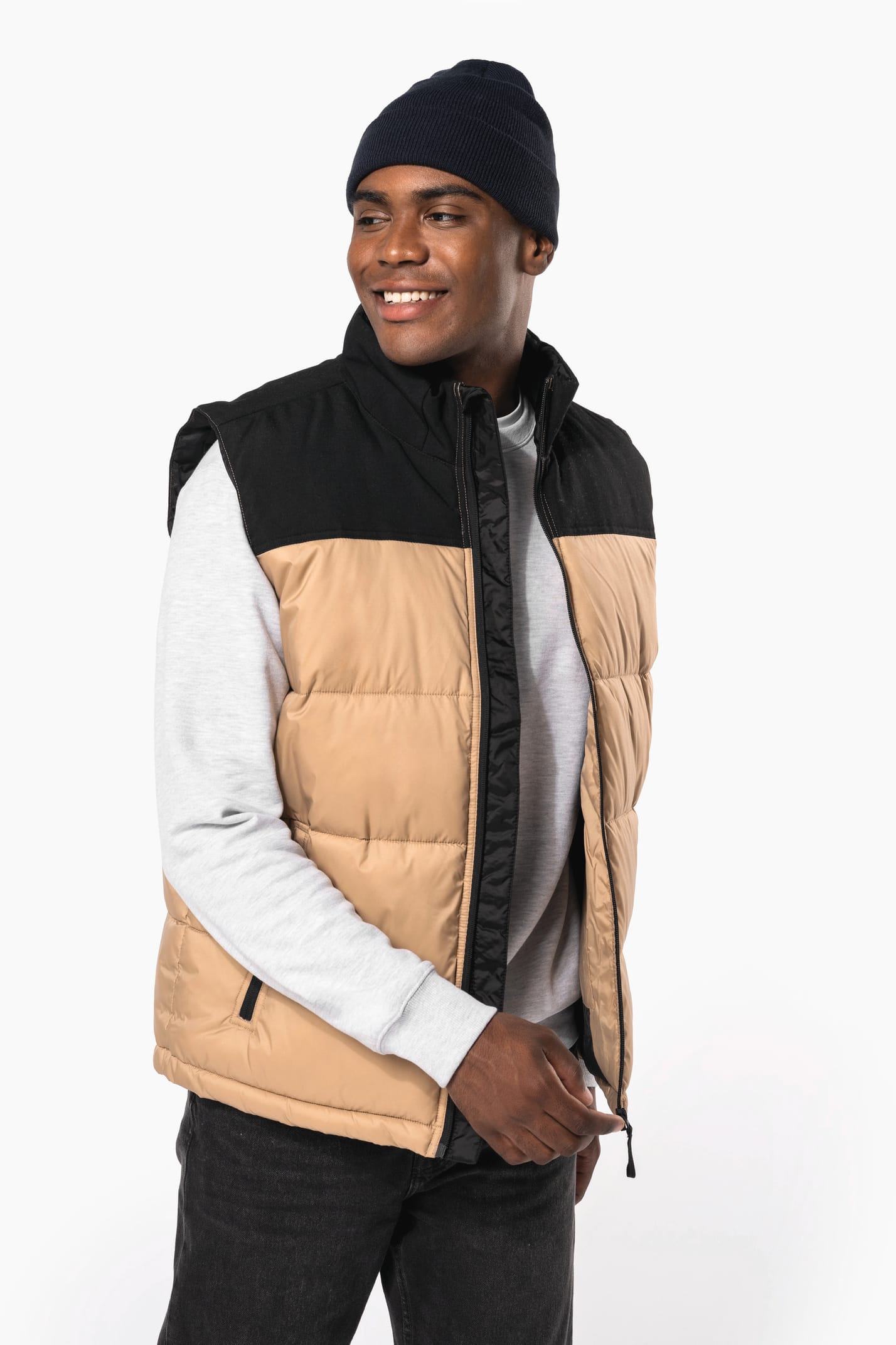 Jeune homme avec bonnet qui porte un bodywarmer matelassé bicolore beige et noir.