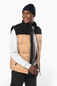 Jeune homme avec bonnet qui porte un bodywarmer matelassé bicolore beige et noir.