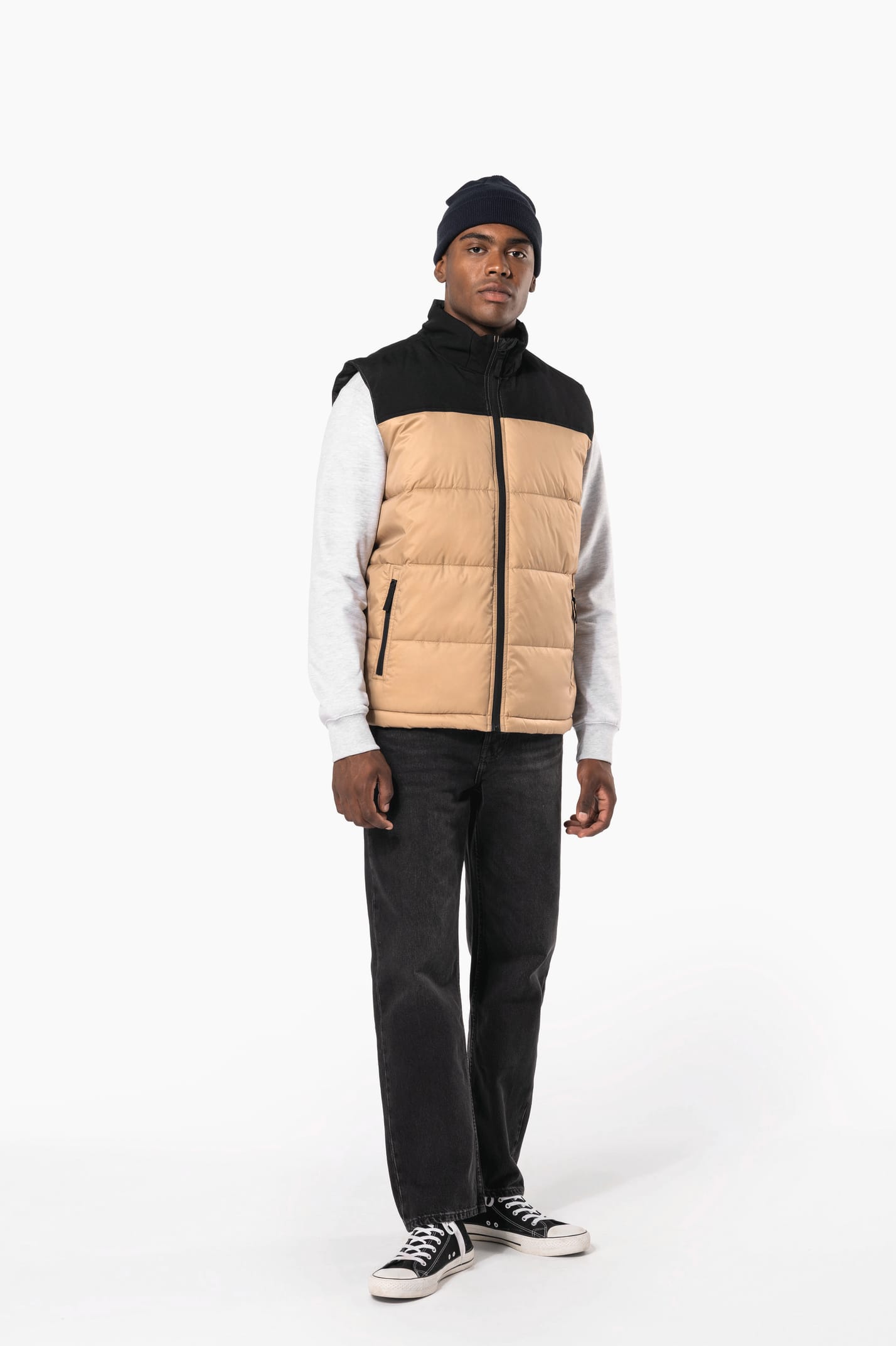 Jeune homme avec bonnet qui porte un bodywarmer matelassé bicolore beige et noir.