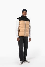 Jeune homme avec bonnet qui porte un bodywarmer matelassé bicolore beige et noir.