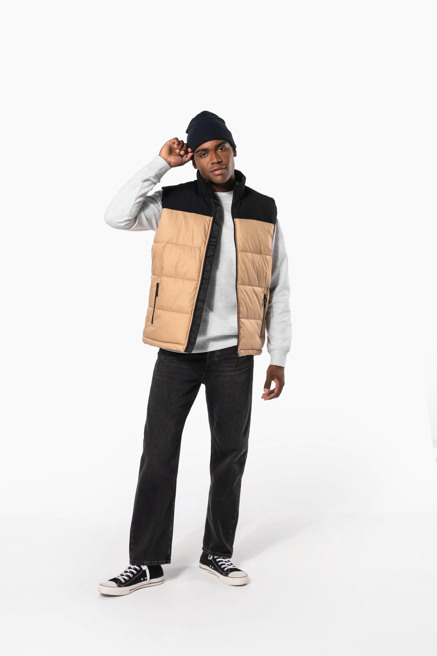 Jeune homme avec bonnet qui porte un bodywarmer matelassé bicolore beige et noir.