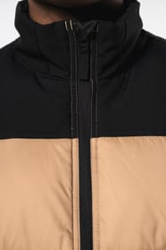 Jeune homme avec bonnet qui porte un bodywarmer matelassé bicolore beige et noir.