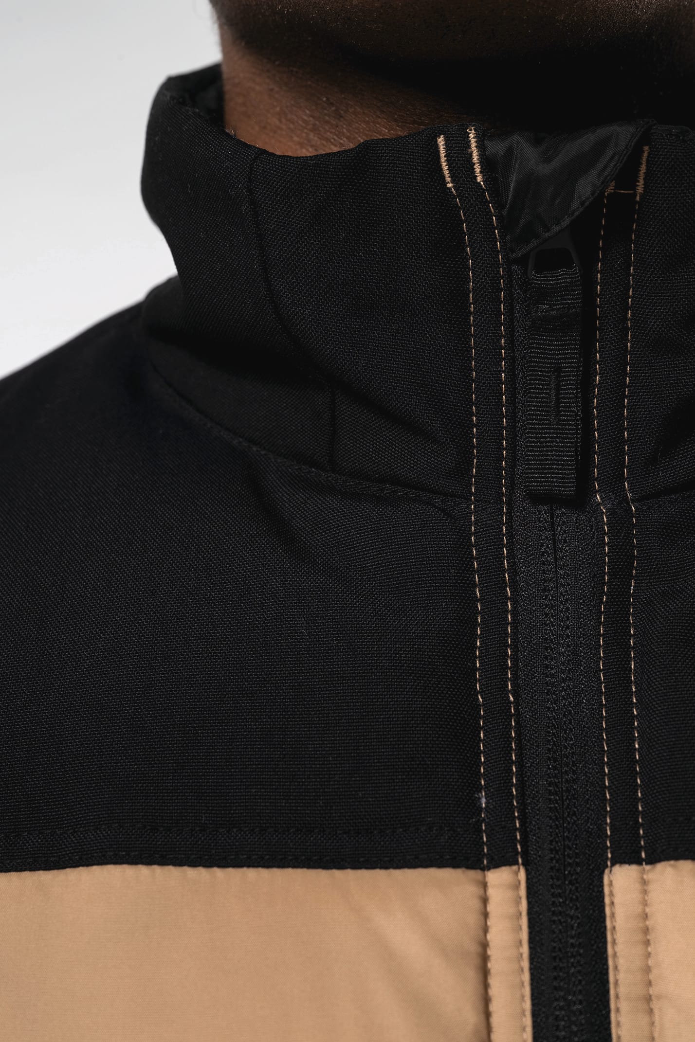 Jeune homme avec bonnet qui porte un bodywarmer matelassé bicolore beige et noir.