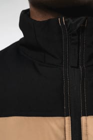 Jeune homme avec bonnet qui porte un bodywarmer matelassé bicolore beige et noir.