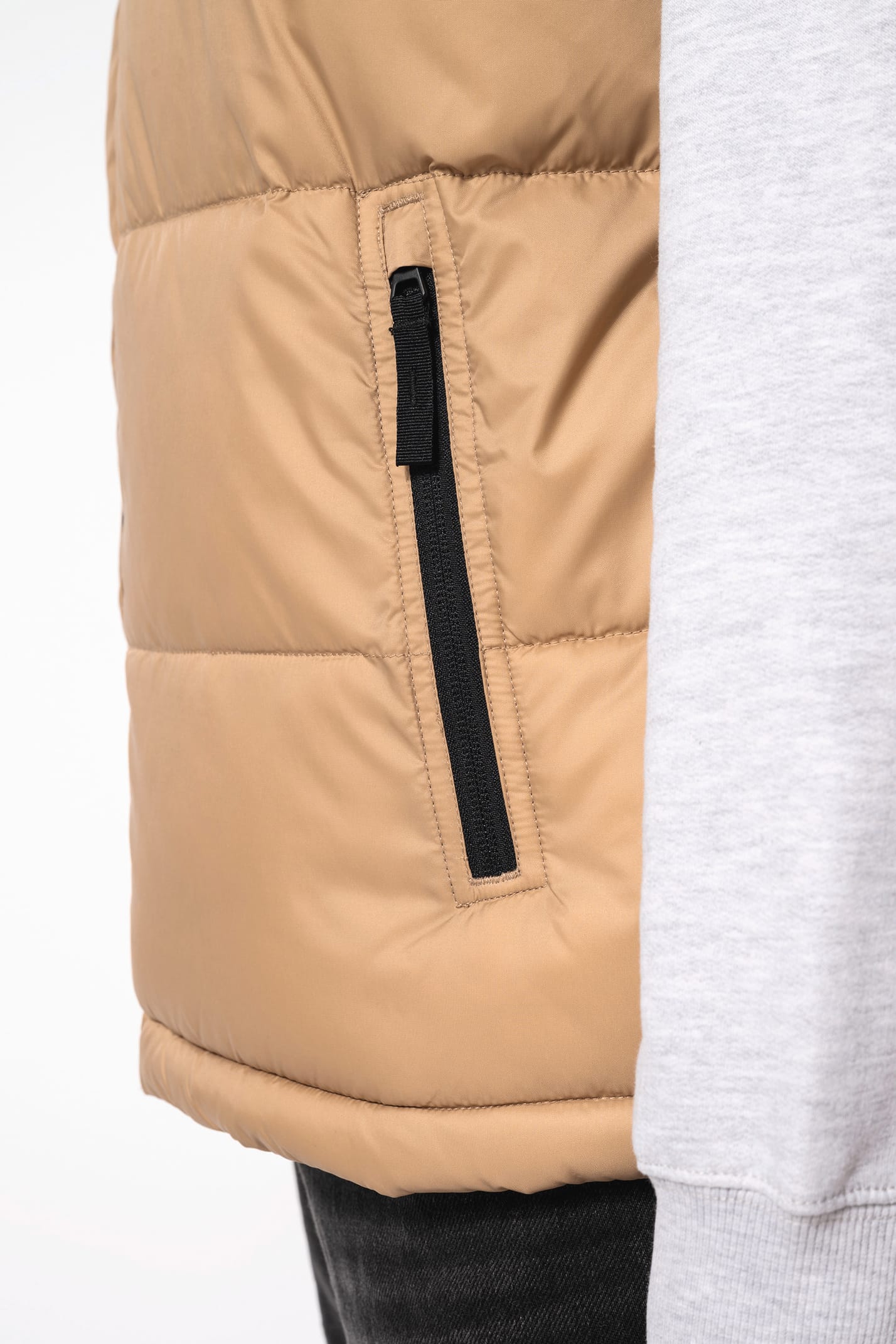Jeune homme avec bonnet qui porte un bodywarmer matelassé bicolore beige et noir.