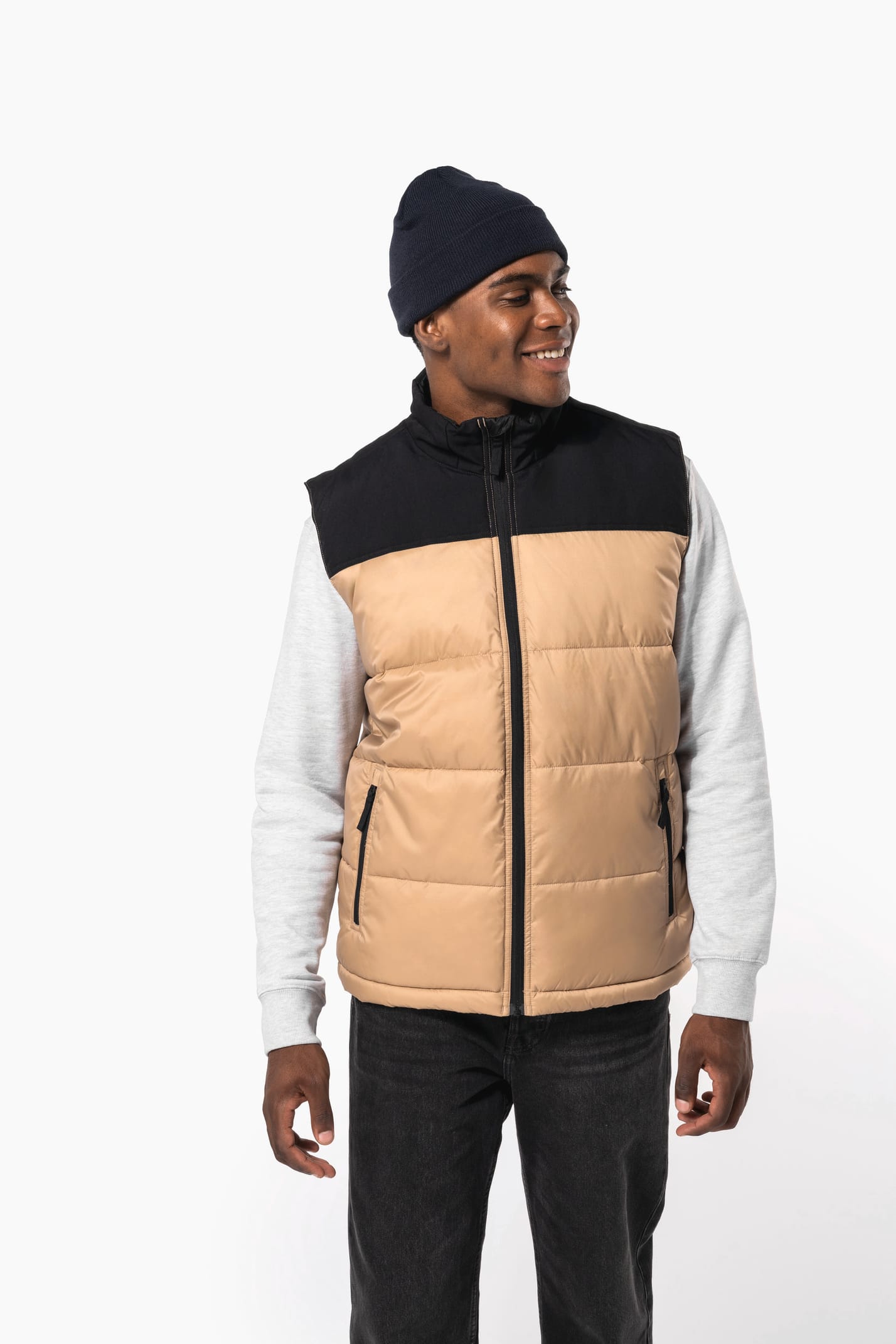 Jeune homme avec bonnet qui porte un bodywarmer matelassé bicolore beige et noir.