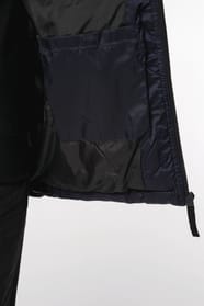 Jeune femme châtain cheveux frisés attachés qui porte une parka matelassée à capuche bi-ton marine et noir.