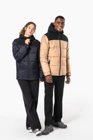 Jeune femme châtain cheveux frisés attachés et homme cheveux courts qui portent des parkas matelassées à capuches bi-ton.