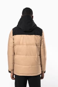 Jeune homme brun cheveux courts qui porte parka matelassée à capuche bi-ton sable et noire.