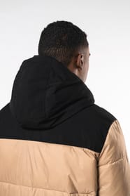 Jeune homme brun cheveux courts qui porte parka matelassée à capuche bi-ton sable et noire.