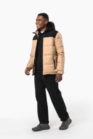 Jeune homme brun cheveux courts qui porte parka matelassée à capuche bi-ton sable et noire.