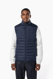 Jeune homme brun cheveux courts qui porte un bodywarmer bi matière bleu marine brillant.