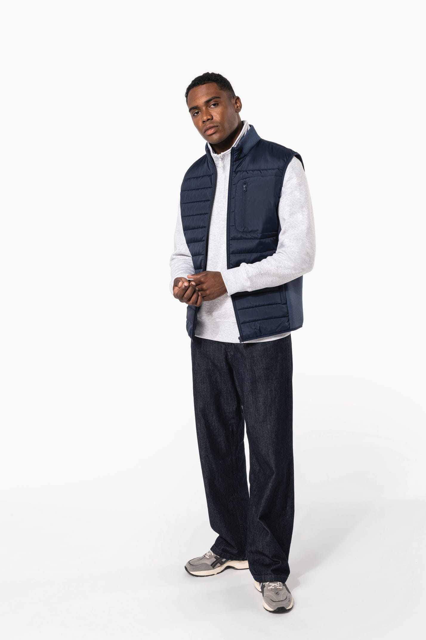 Jeune homme brun cheveux courts qui porte un bodywarmer bi matière bleu marine brillant.