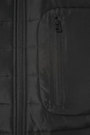 Jeune homme brun cheveux courts qui porte une veste bi matière noire et grise.