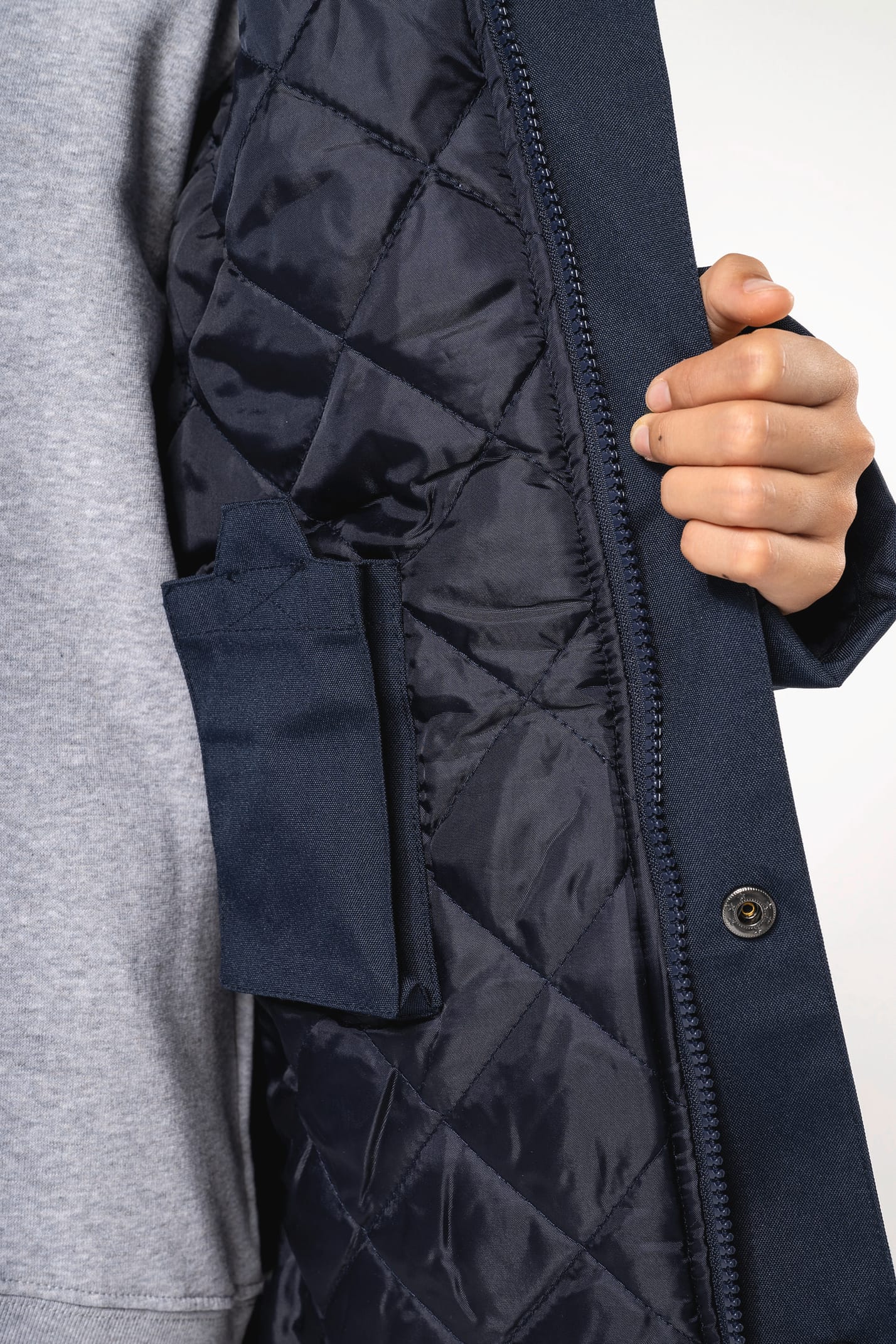 Jeune fille brune cheveux attachés qui porte une parka Navy.
