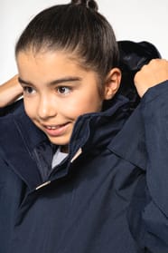 Jeune fille brune cheveux attachés qui porte une parka Navy.