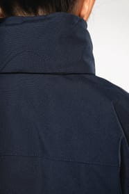 Jeune fille brune cheveux attachés qui porte une parka Navy.