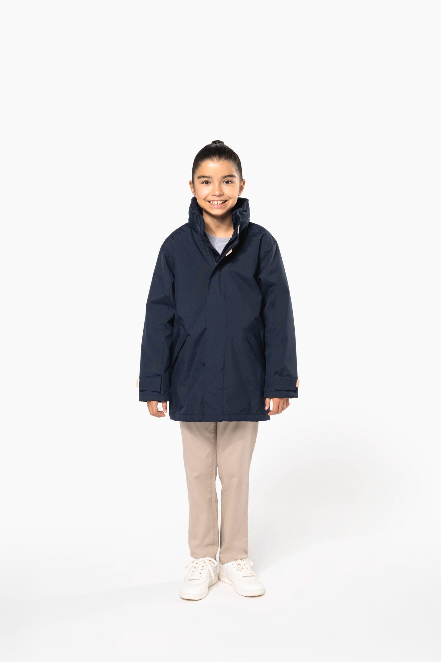 Jeune fille brune cheveux attachés qui porte une parka Navy.