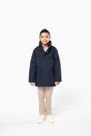 Jeune fille brune cheveux attachés qui porte une parka Navy.
