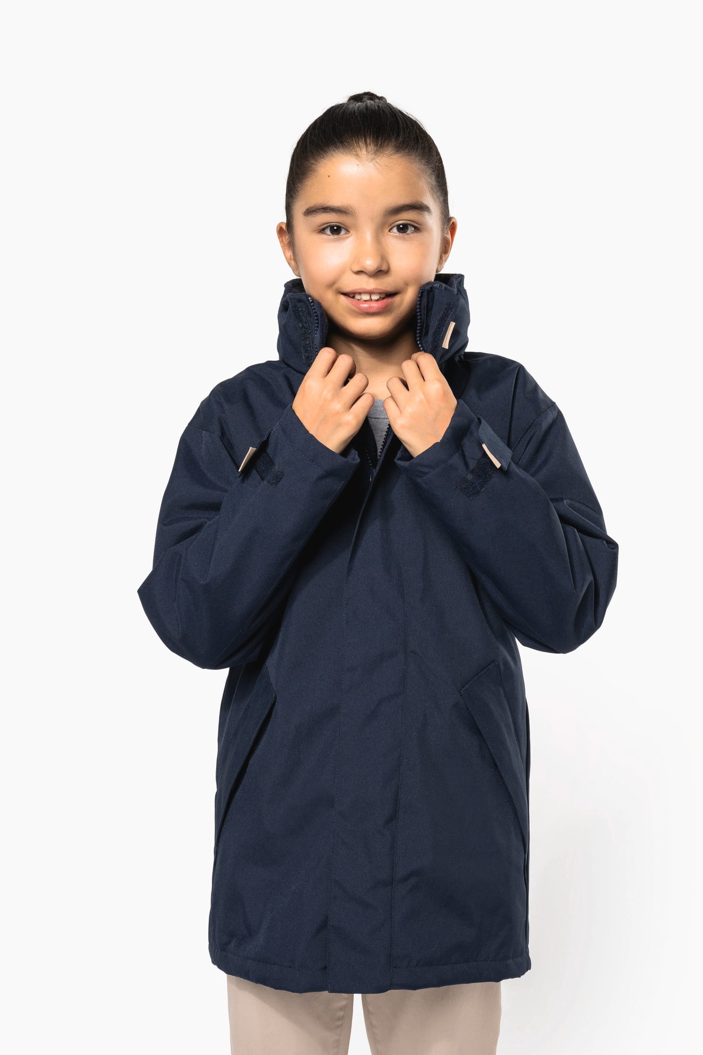 Jeune fille brune cheveux attachés qui porte une parka Navy.