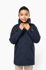 Jeune fille brune cheveux attachés qui porte une parka Navy.